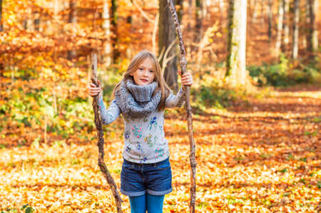 Outdoor portrait of a cute little girl in autumn forestの写真素材