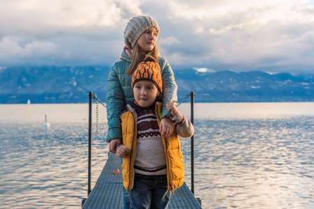 Late evening portrait of two adorable kids playing by the lake Geneva, Switzerlandの写真素材