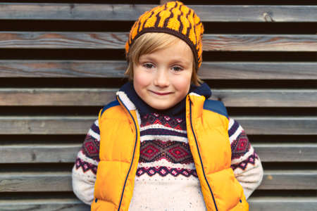 Outdoor portrait of a cute little boy, wearing warm pullover and yellow vestの写真素材