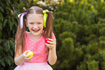 Cute little girl with 2 pigtails playing in the park, egg huntingの写真素材