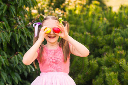 Cute little girl with 2 pigtails playing in the park, egg huntingの写真素材