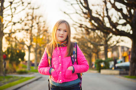 Cute little girl of 8 years old wearing backpack, walking to schoolの写真素材