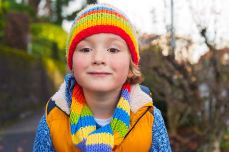 Outdoor portrait of adorable toddler boy wearing colorful hat and scarfの写真素材