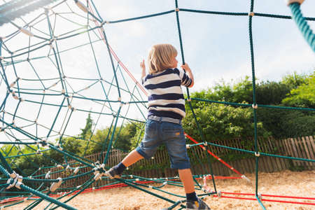 Cute little boy having fun on playground, wearing swearshirt and denim shortsの写真素材