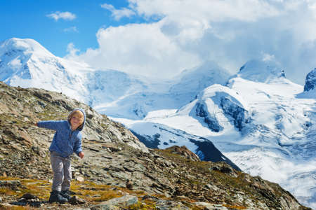 Cute kid boy resting in Alps, wearing warm knitted jacket and mountain bootsの写真素材