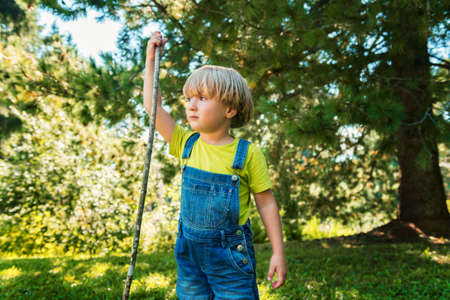 Little boy playing outdoors on a nice sunny summer day wearing denim overallsの写真素材