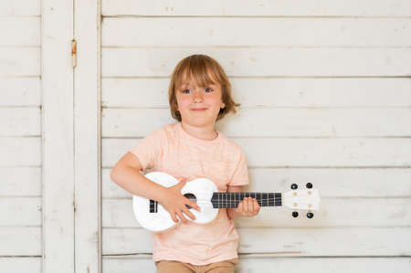 Little happy boy plays his guitar or ukuleleの写真素材