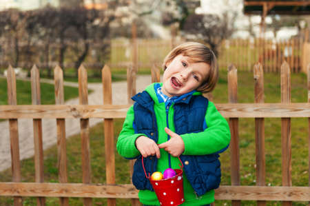 Cute little boy with bucket full of colorful easter eggs