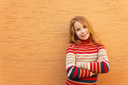 Fashion close up portrait of adorable redheaded girl against orange wall, wearing stripes roll neck pulloverの写真素材