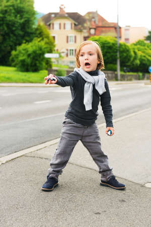 Outdoor portrait of a cute fashion boy in the street, wearing, grey clothes and dark blue shoesの写真素材