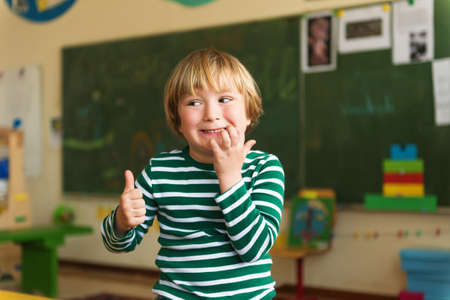 Indoor portrait of a cute little boy in a classroomの写真素材