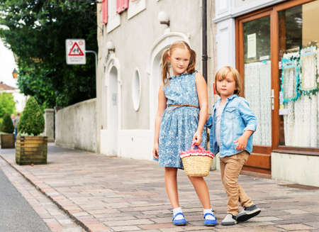 Portrait of fashion kids in a city, cute kids posing outdoors, adorable little girl and her brother wearing blue clothesの写真素材