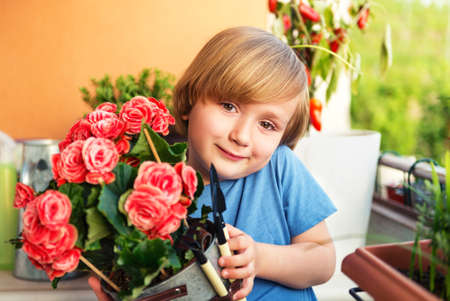 Cute little boy playing with garden tools on the balconyの写真素材