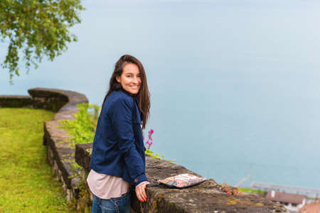 Young brunette woman resting in Lavaux region, Switzerland. Admire Lake Geneva from the top of the hillの写真素材