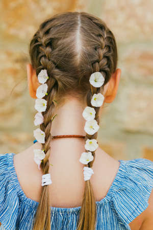 White morning glory flowers in little girl's braidsの写真素材