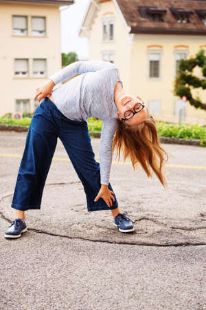 Outdoor funny portrait of a cute little girl of 8-9 years old, wearing blue clothes and glasses