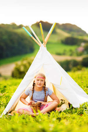 Outdoor portrait of a cute little girl playing musicの写真素材