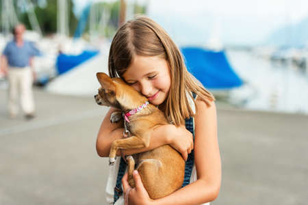 Beautiful little girl hugging chihuahuaの写真素材