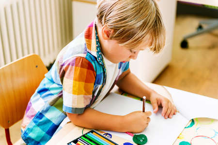 Indoor portrait of a cute little boy in a classroomの写真素材