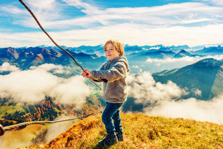 Portrait of a cute little boy in mountains, wearing grey jacket and mountain boots, Moleson-sur-Gruyeres, canton of Fribourg, Switzerlandの写真素材