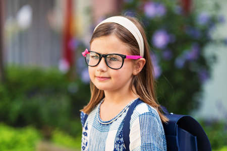 Pretty little 9 year old girl walking back to school, wearing glasses and blue backpackの写真素材