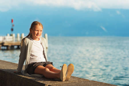 Cute little girl resting by lake Geneva at sunsetの写真素材