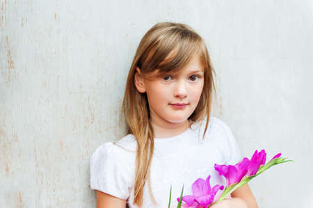 Close up portrait of a cute little 7 year old girl with purple flowerの写真素材