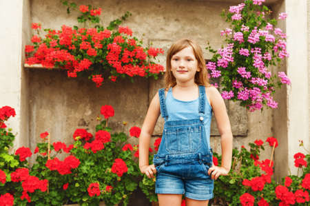 Summer portrait of a little girl of 6 years old, wearing denim overallsの写真素材