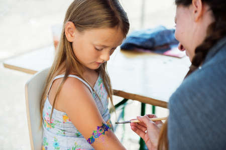 Little girl getting glitter tattoo at birthday partyの写真素材