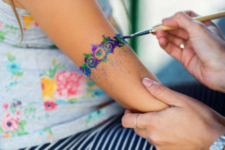 Little girl getting glitter tattoo at birthday partyの写真素材