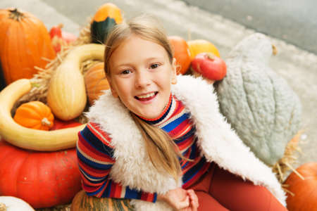 Adorable little girl of 8-9 year old choosing halloween pumpkin on farm market, having fun with unusual different kind of pumpkinsの写真素材