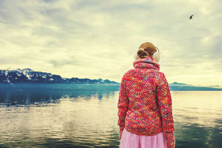 Adorable little girl admiring lake Geneva on a cold winter day, wearing warm pink pullover and earmuffs, back viewの写真素材