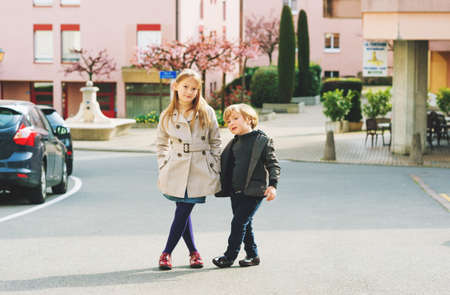 Two fashion kids models posing outdoors on nice spring day, wearing stylish jacketsの写真素材