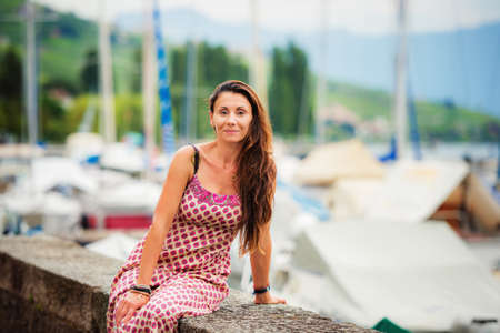 Outdoor summer portrait of a beautiful brunette woman resting by the lake