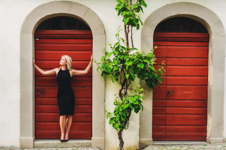 Outdoor portrait of young blond woman wearing black dress and high heel shoesの写真素材