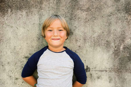 Outdoor fashion portrait of adorable 5-6 year old little blond boy wearing t-shirtの写真素材