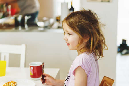Little 3 year old girl having breakfast at home