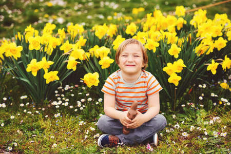 Cute little kid boy with chocolate Easter bunny celebrating traditional feast. Family, holiday,...