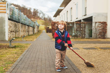 Cute little boy sweeping the backyard on a early spring dayの写真素材