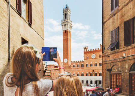 Kids taking picture with the smartphone of Piazza del Campo, Siena, Italyの写真素材