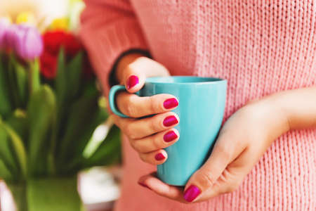 Cup of coffee in woman's hands with bright pink manicureの写真素材
