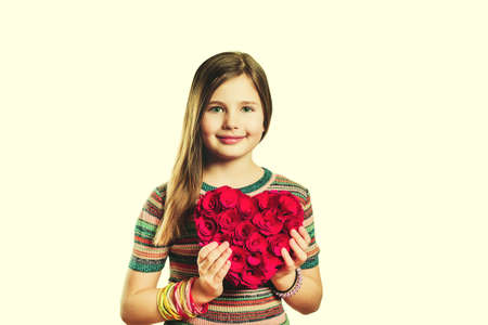 Studio shot of young little 9-10 year old girl, wearing stripe dress, isolated on white background,  holding big decoration heart, Saint Valentine concept, toned imageの写真素材