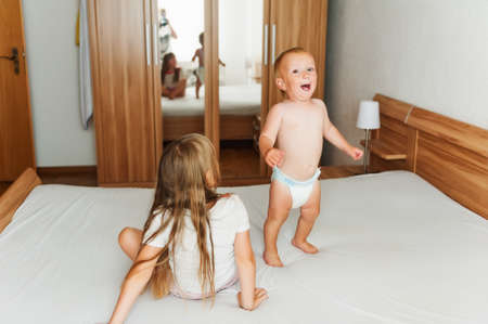 Mother taking pictures of two happy kids jumping on the bedの写真素材