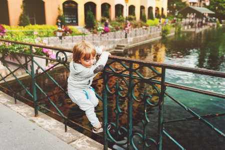 Outdoor portrait of a cute little blond boy looking at beautiful canal in Annecy, France. Travel with kidsの写真素材