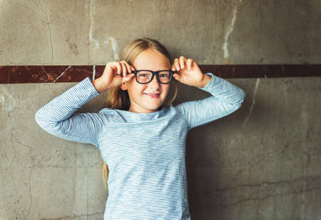 Interior portrait of a cute school girl wearing glasses, stripy shirtの写真素材