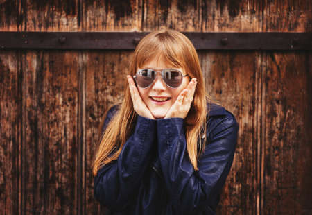 Outdoor fashion portrait of funny 9-10 year old girl wearing sunglasses and blue leather jacketの写真素材