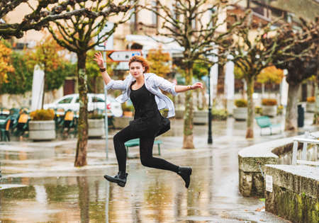 Happy young girl under the rain, jumping over puddlesの写真素材