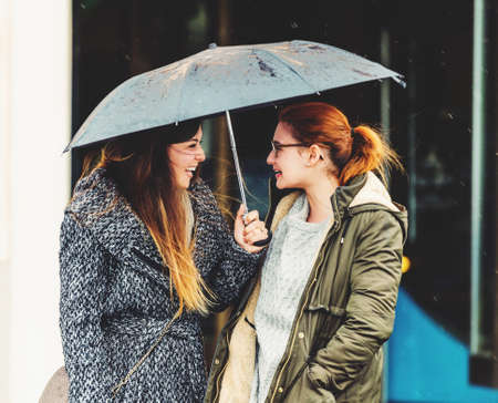 Two 20-25 year old girls under the rain, wearing warm jackets, early spring weatherの写真素材