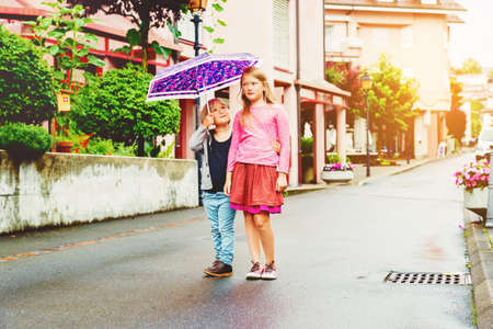 Adorable kids having fun outdoors, playing under the rainの写真素材