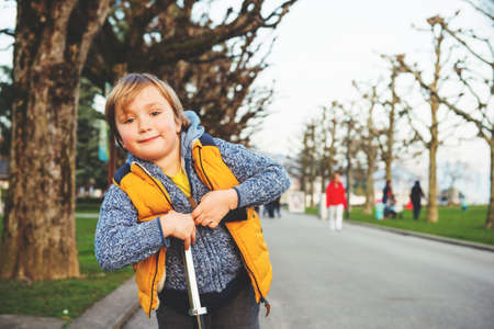 Little boy riding scooter in the park in early springの写真素材